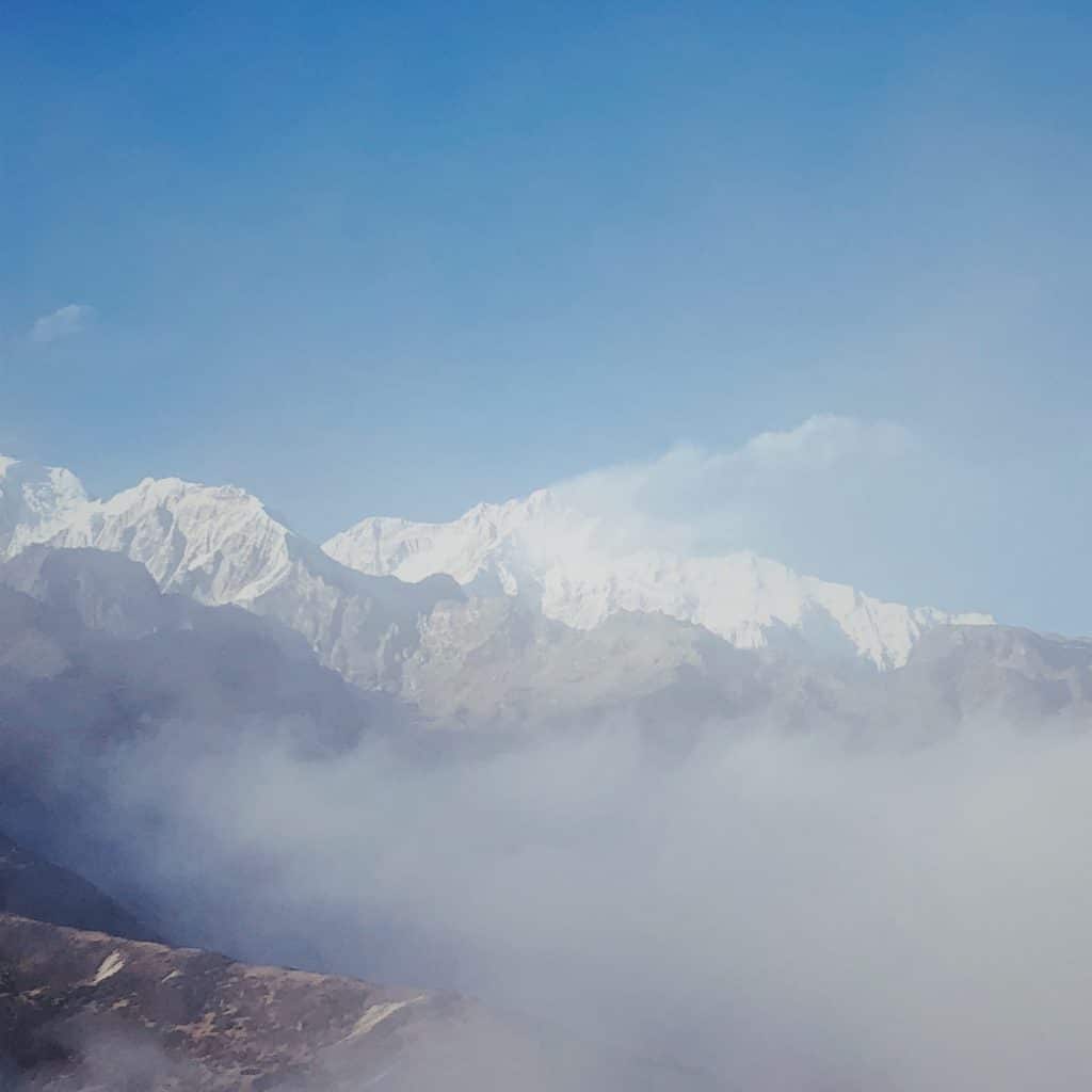 Mount Kanchenjunga, shrouded in fog, with a snow plume blown off the summit.